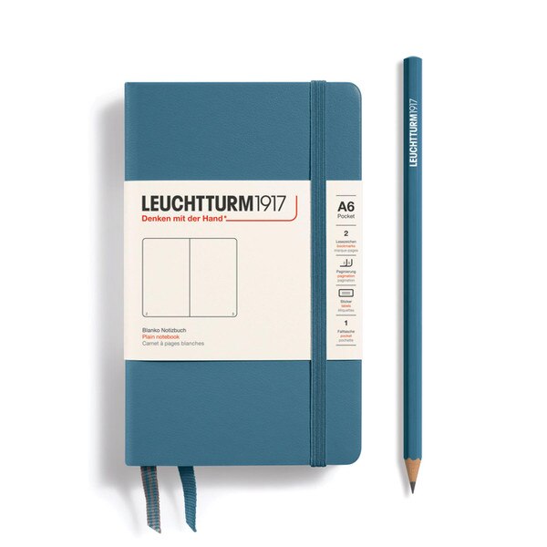 This is a small, greyish-blue notebook with an elastic and two bookmarks. The pages are blank other than page numbers in the bottom corners.